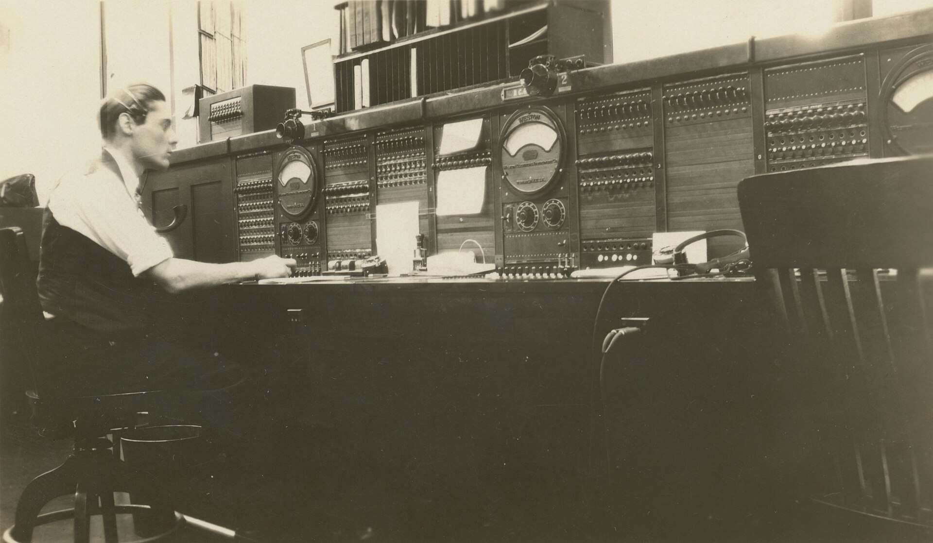 An operator seated at a large telephone switchboard with dials and jacks, Milwaukee, 1930